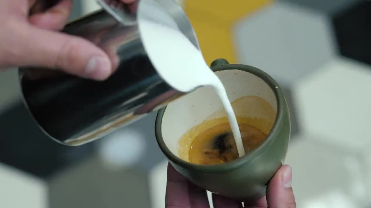 Barista gießt Milchschaum in eine Tasse Espresso