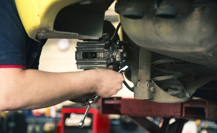 Mechaniker montiert einen Bremssattel an einem aufgebockten Auto