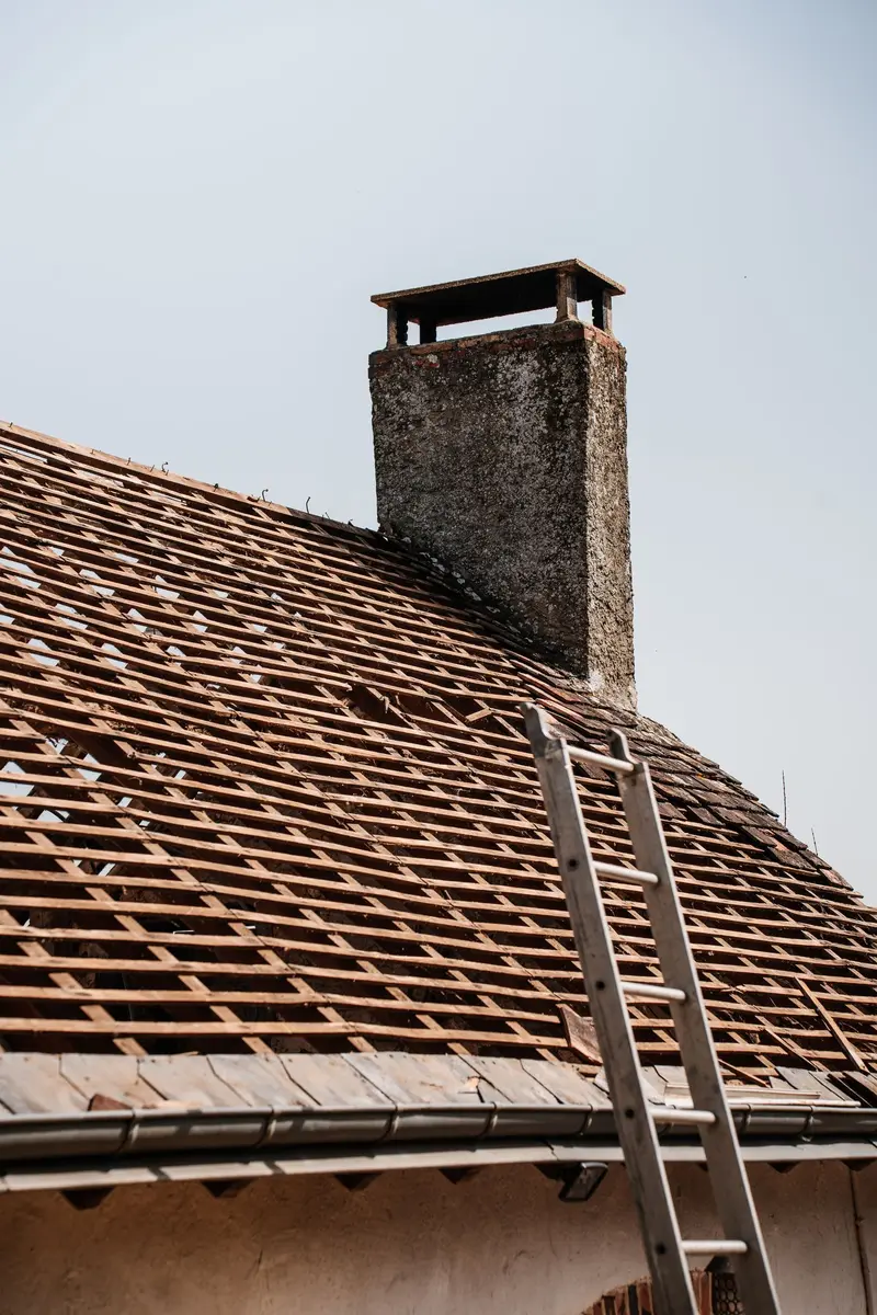Altes Ziegeldach mit Kamin und Leiter vor der Sanierung