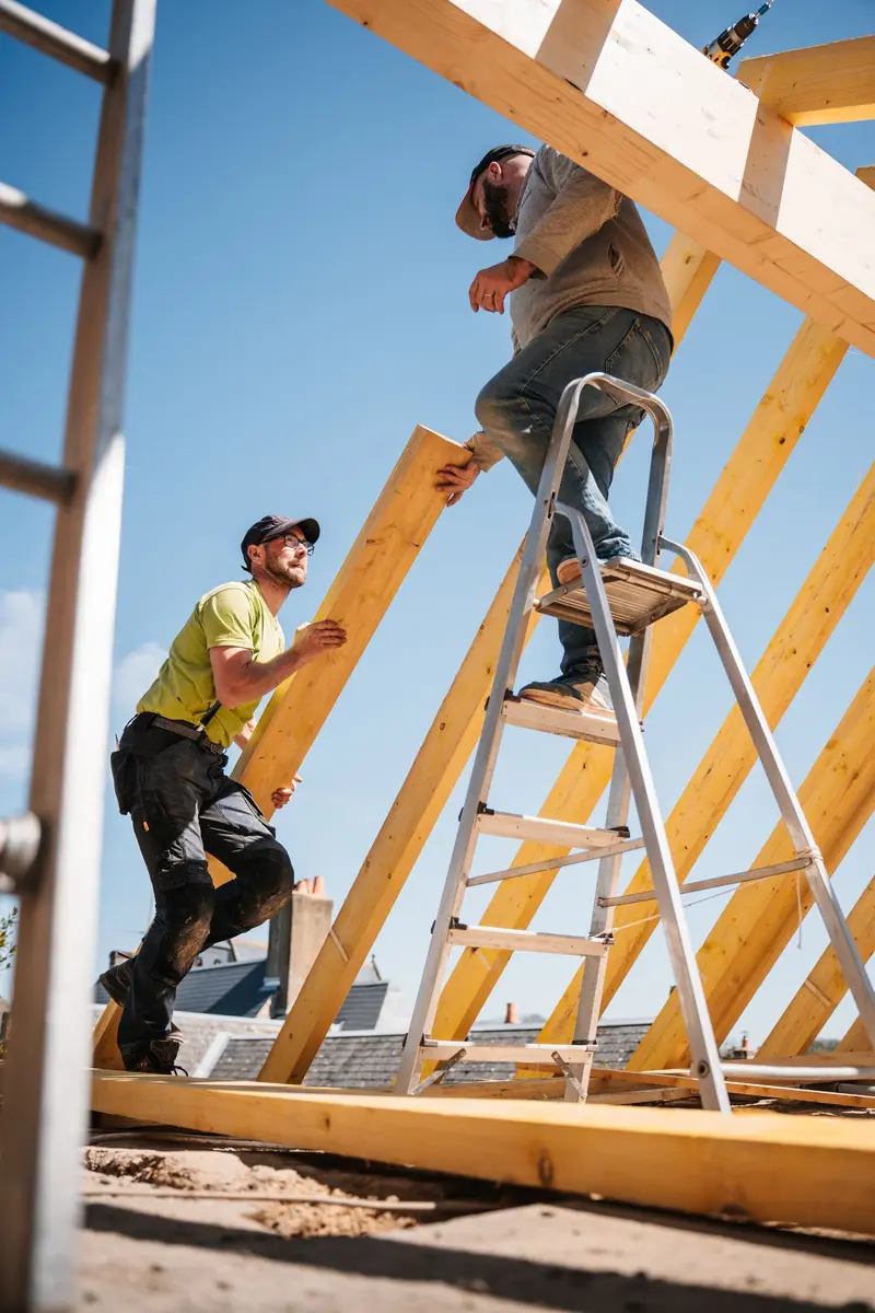 Zwei Handwerker bauen einen neuen Dachstuhl aus Holz