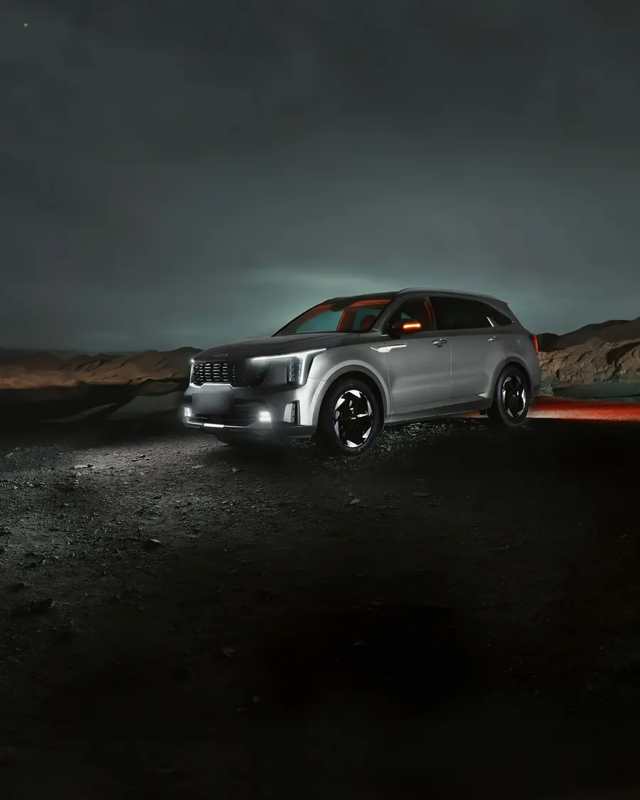 Silberner SUV bei Nacht vor dunklen Hügeln