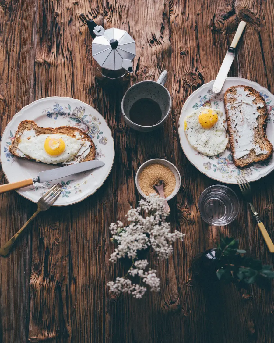 Frühstück auf einem rustikalen Holztisch mit Spiegelei, Brot und Kaffee