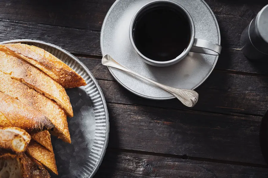 Schwarzer Kaffee und frisches Gebäck auf dunklem Holz
